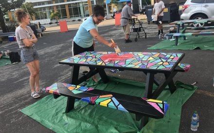 local artist painting picnic tables