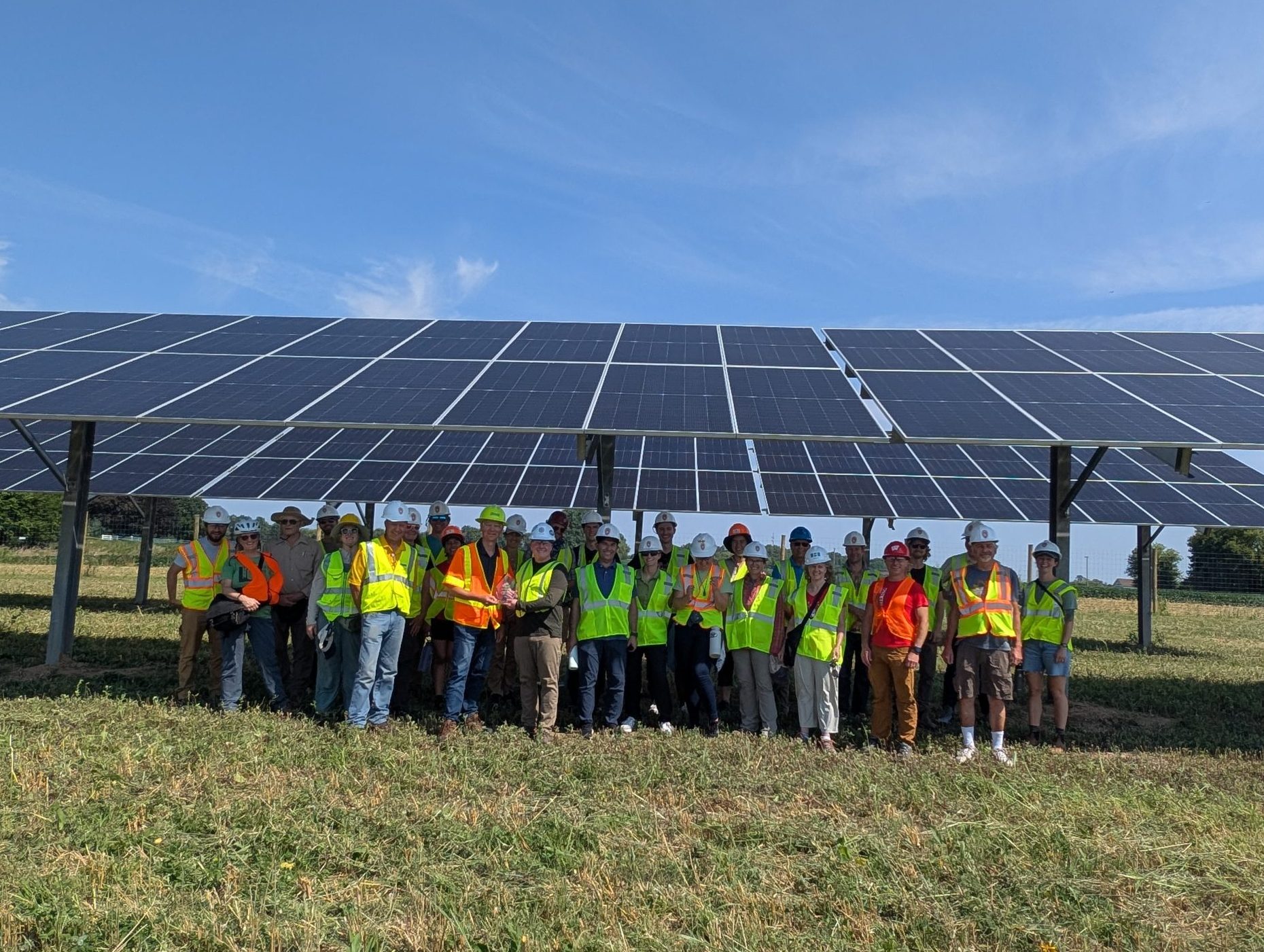 Group standing under a completed solar facility